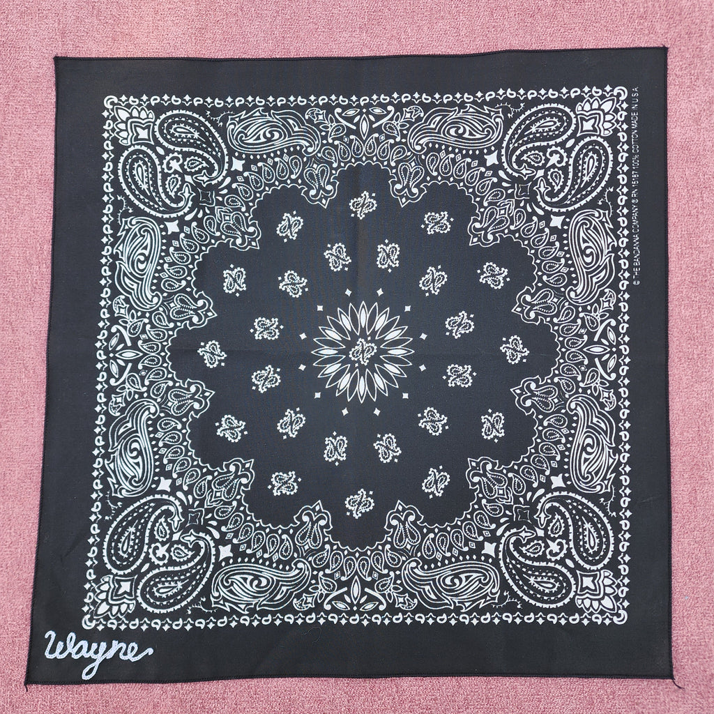 Black bandana with white paisley pattern on a pink background